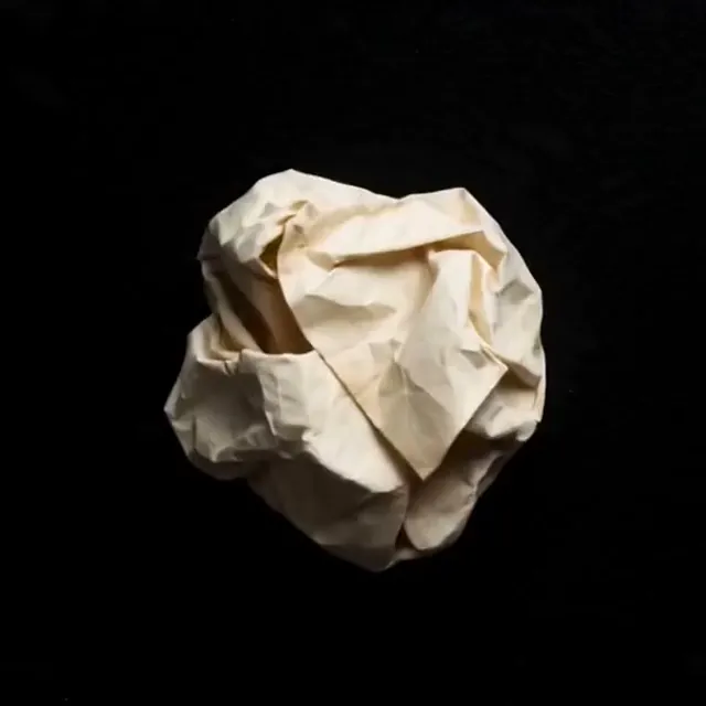 Crumpled paper note unfolding to show handwritten text